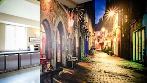 A lobby with a large mural of a cobblestone street at night, a reception desk, and a seating area with a bench. - Kinlay Hostel Galway (Galway)