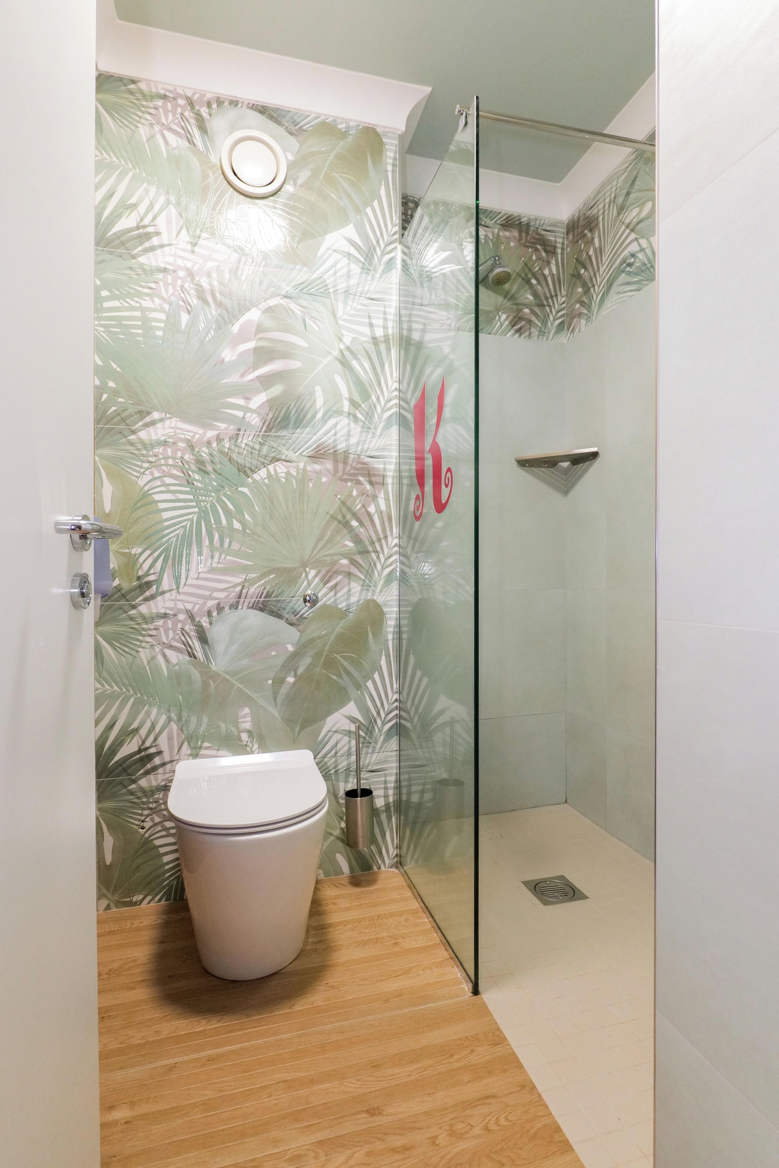 A bathroom with a toilet, a shower, and a glass door.