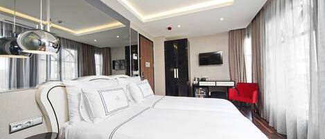 A hotel room with a large bed, a desk with a chair, a TV, and a mirror.
