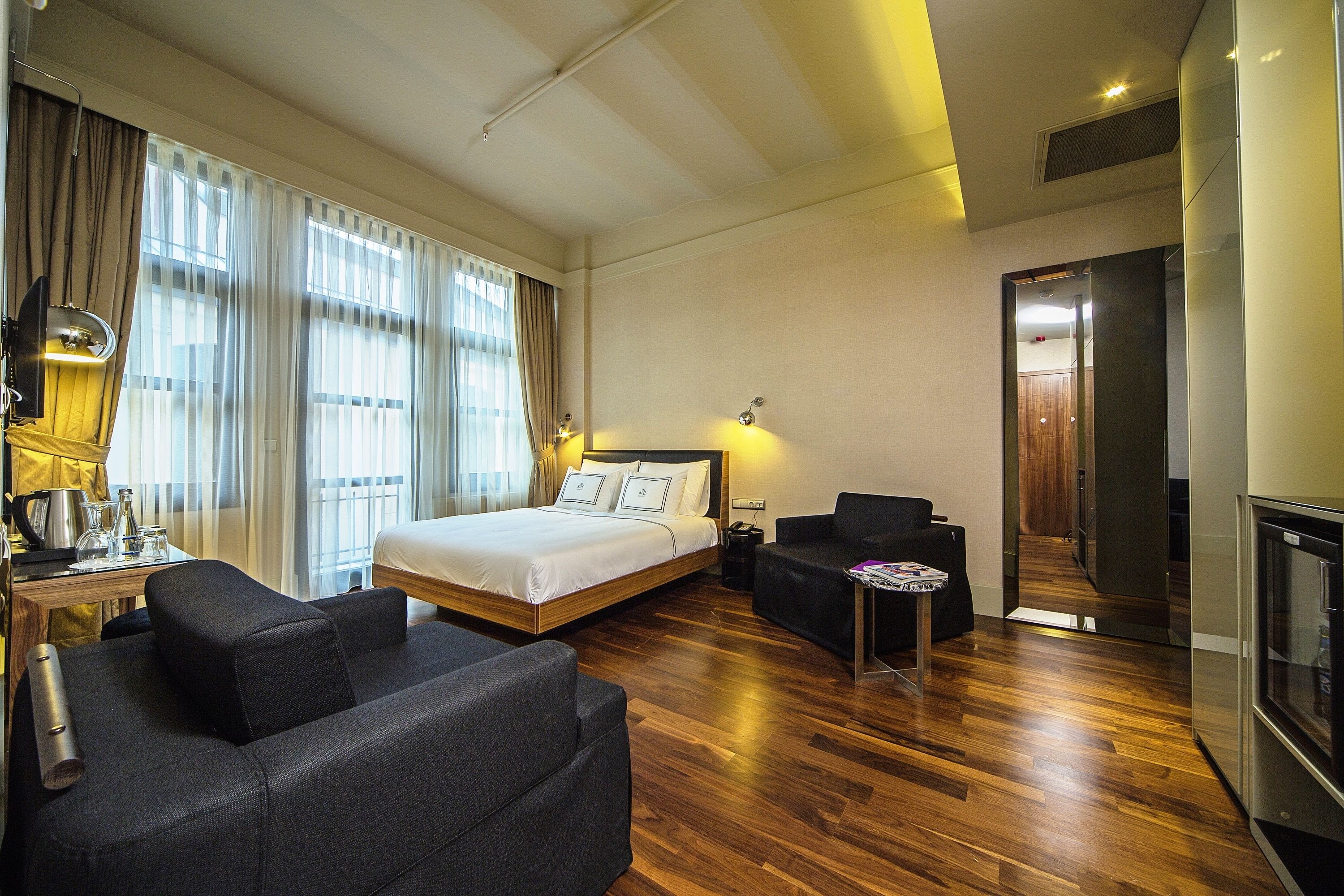 A hotel room with a bed, a sofa, a small table, and a TV.