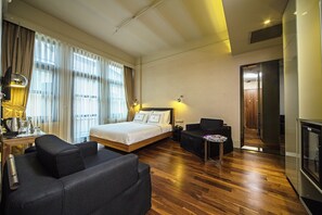Una habitación de hotel con cama, sofá, una mesita y televisor.