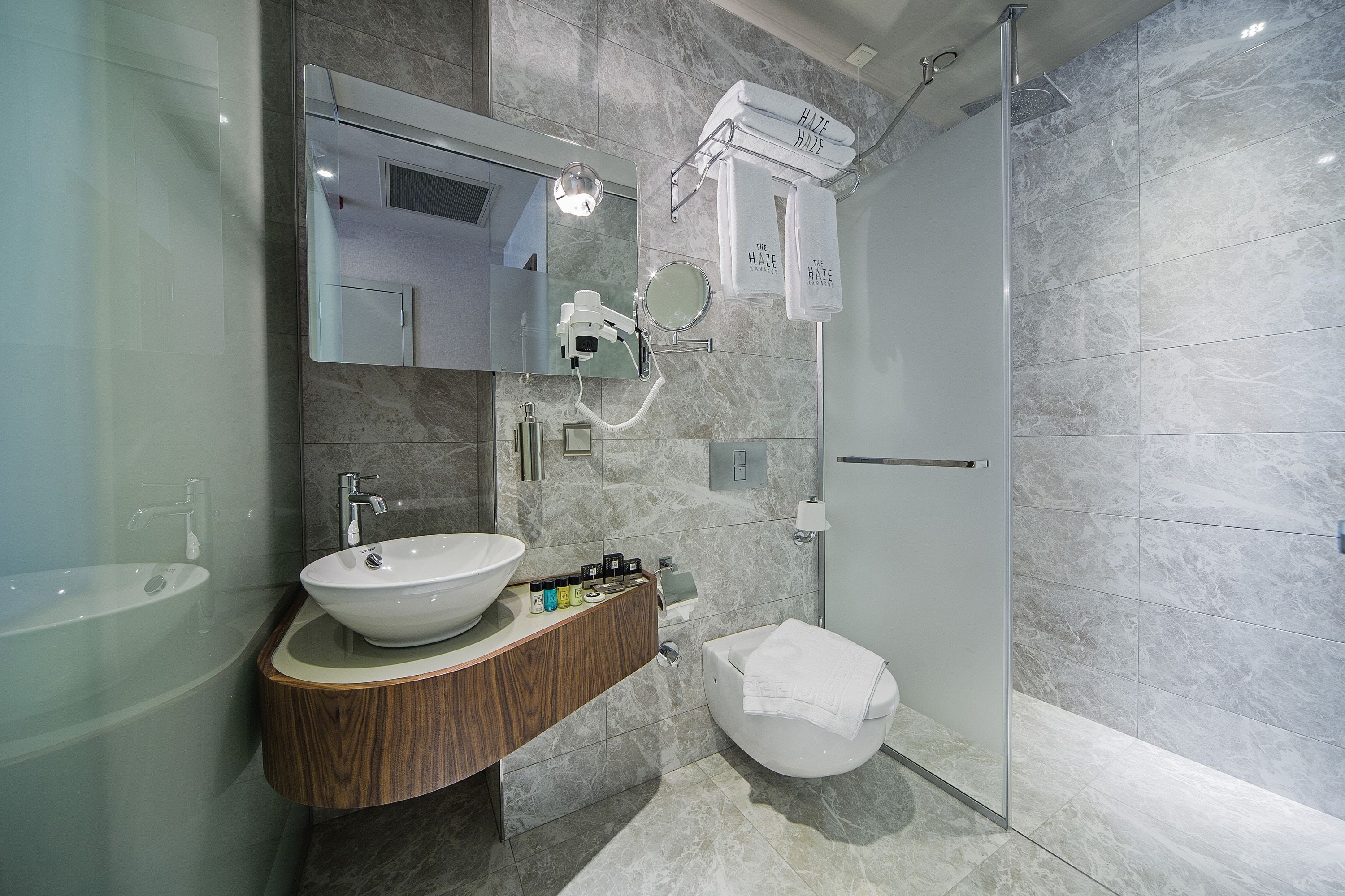 A modern bathroom with a large sink, mirror, and shower.