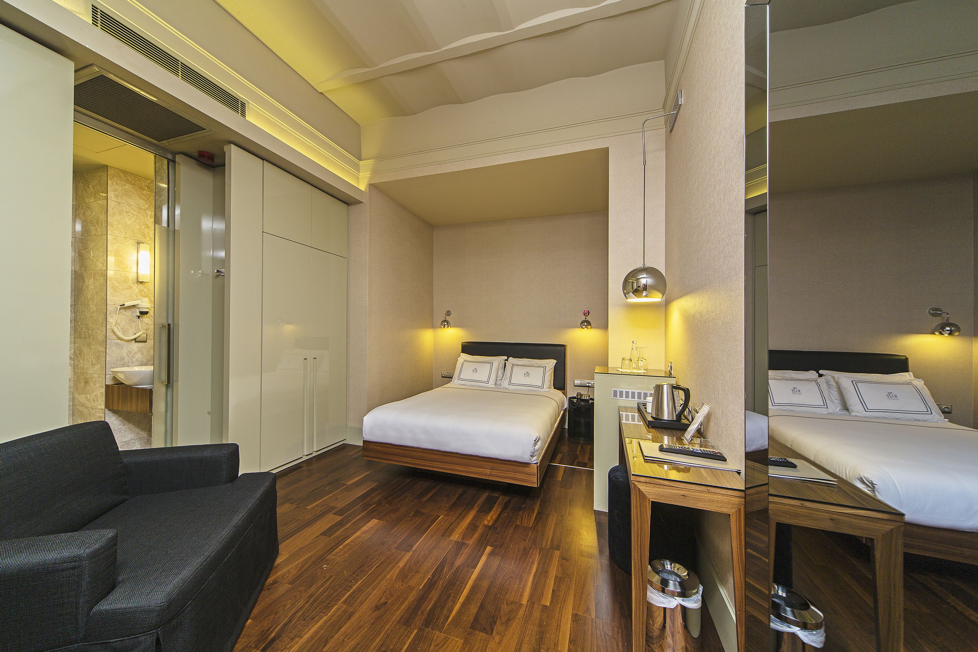 Une chambre d’hôtel comprenant un lit, une table de chevet et un coin salon avec un fauteuil.