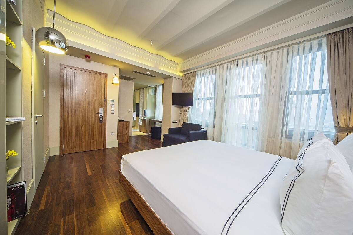 A hotel room with a large bed, a desk, a chair, a television, and a bathroom.