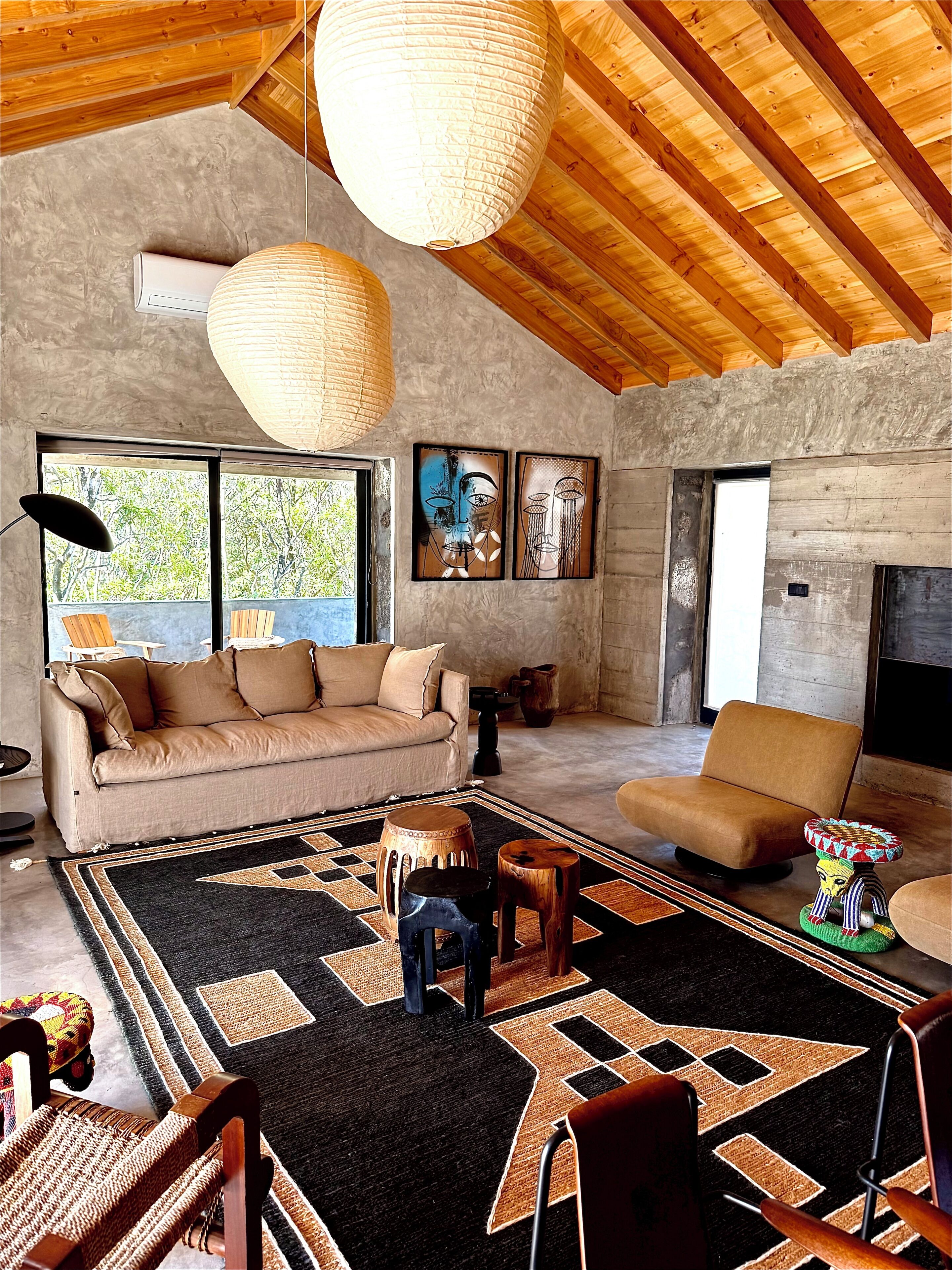 A spacious living area with a high ceiling, a large window, a sofa, a coffee table, and a fireplace.