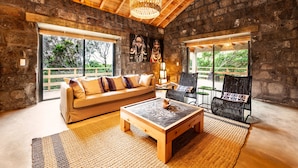 A cozy living room with a stone wall, wooden ceiling, and large windows. - Pocinhobay (Madalena)