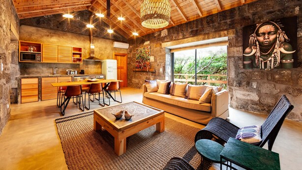 A rustic interior with a wooden ceiling, a dining area, a sofa, and a large window. - Pocinhobay (Madalena)