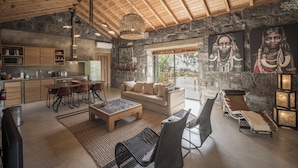A spacious living area with a stone wall, wooden ceiling, and a dining set. - Pocinhobay (Madalena)