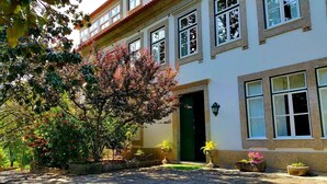 Un edificio de dos pisos con una puerta verde, varias ventanas y plantas en macetas en el patio.