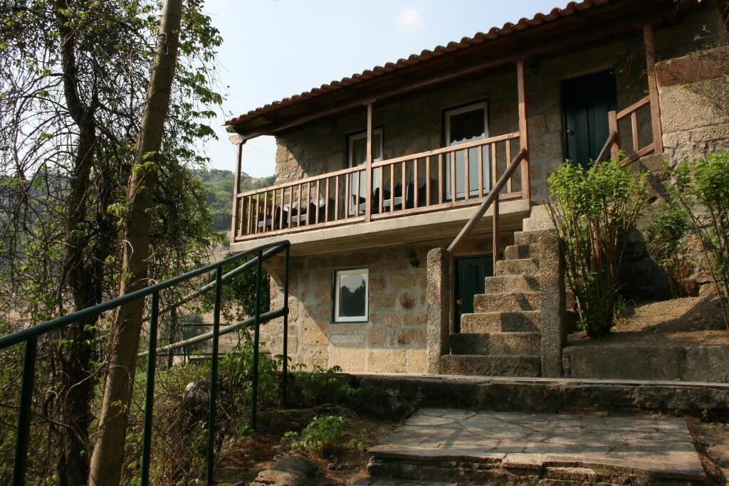 A stone building with a balcony, steps, and a view of the surrounding landscape.