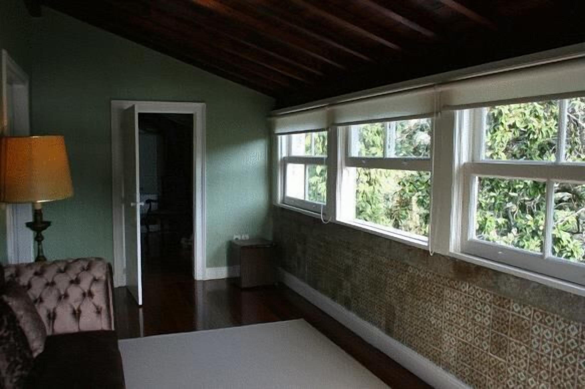 Una habitació amb sostre de fusta, paret amb dibuixos i finestra amb vista a vegetació.