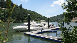 Un puerto deportivo con un yate amarrado, rodeado de exuberante vegetación y colinas.
