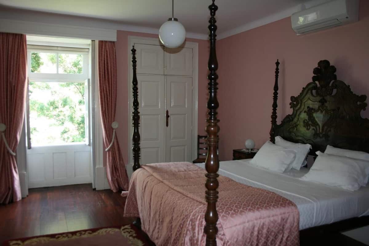 Une chambre à coucher avec un lit à baldaquin, une porte blanche et une fenêtre avec des rideaux.