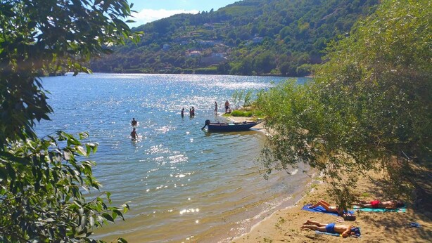 Un lago con gente nadando y un bote en la orilla.