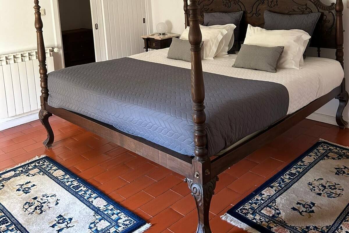 Un lit à baldaquin avec une tête de lit en bois, une porte blanche et un sol carrelé.
