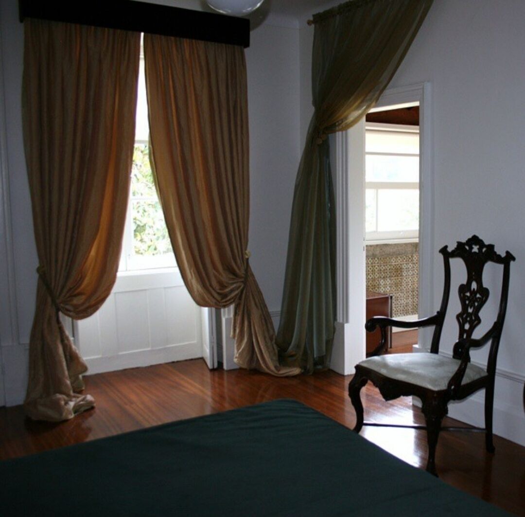 A room with a bed, wooden floor, and a chair.