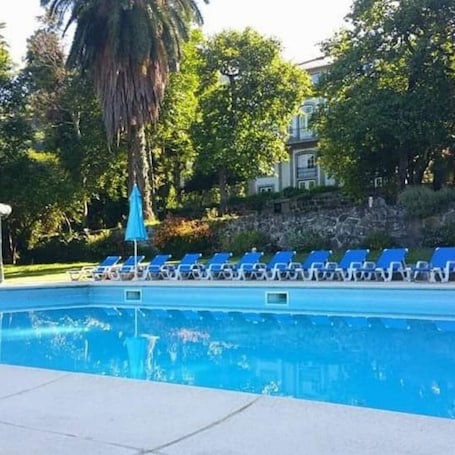Una piscina al aire libre, sillones reclinables de piscina