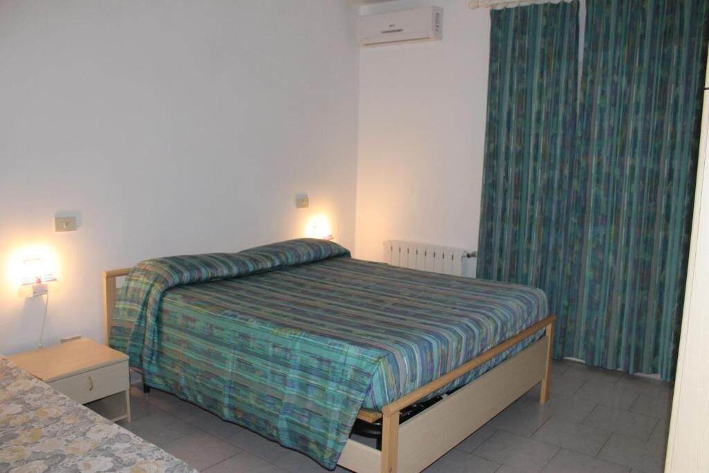 Ein kleines, schlichtes Zimmer mit einem Einzelbett, einem Nachttisch und einer Heizung.