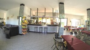 A spacious restaurant with a central bar, multiple seating areas, and a tiled floor.