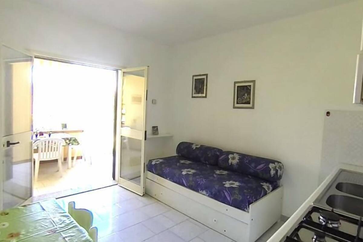A small, bright room with a sofa, a dining table, and a kitchen area.