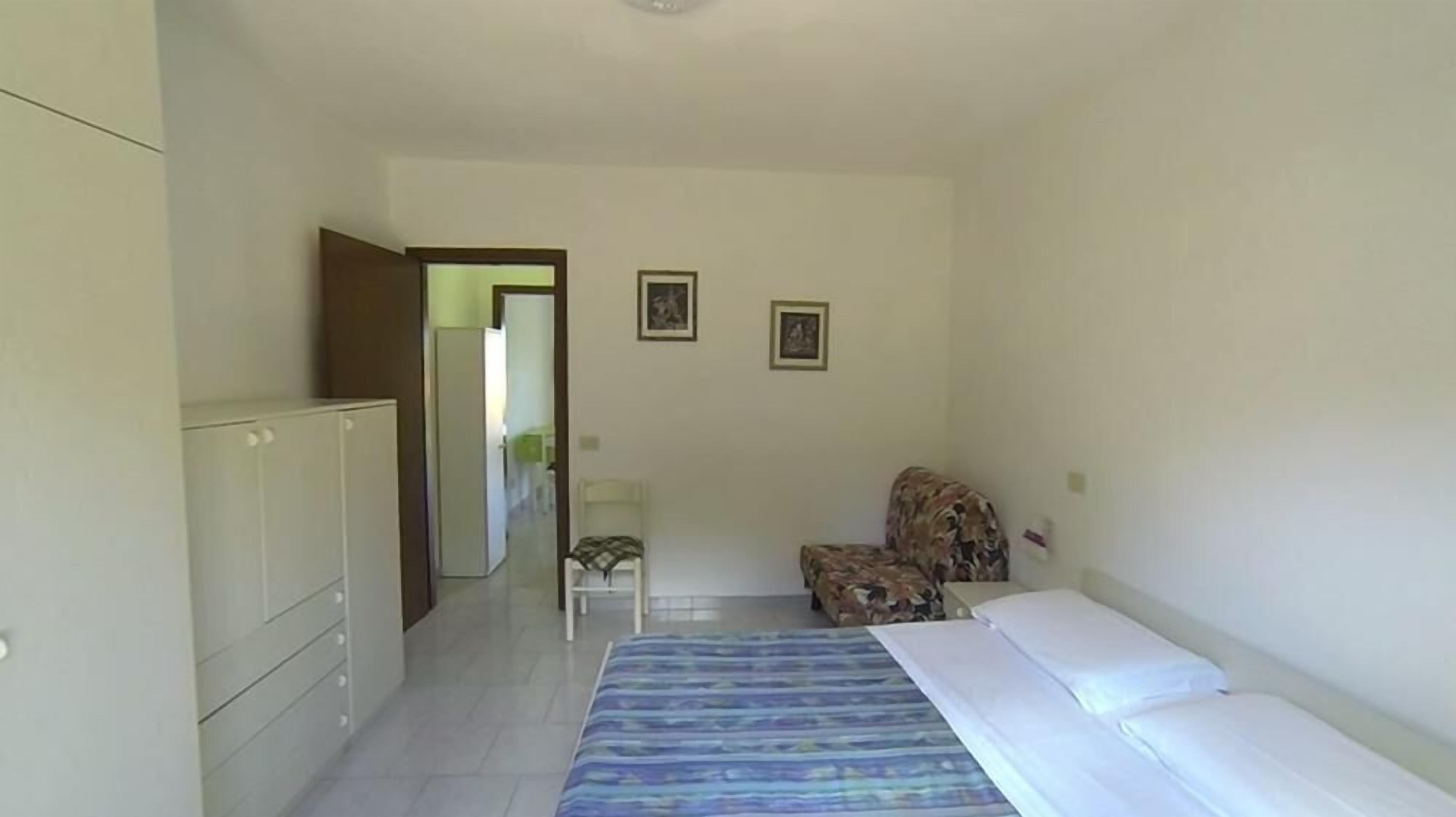 Une chambre à coucher comprenant un lit, une chaise, une armoire et deux tableaux encadrés accrochés au mur.