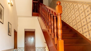 A wooden staircase with a handrail, a door at the bottom, and patterned wall tiles. - Quinta de São Caetano (Viseu)