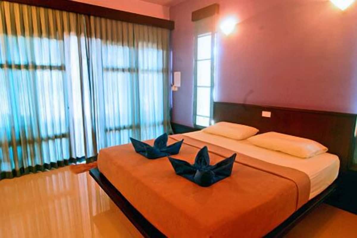 Quarto de hotel com cama, cortinas e janela.