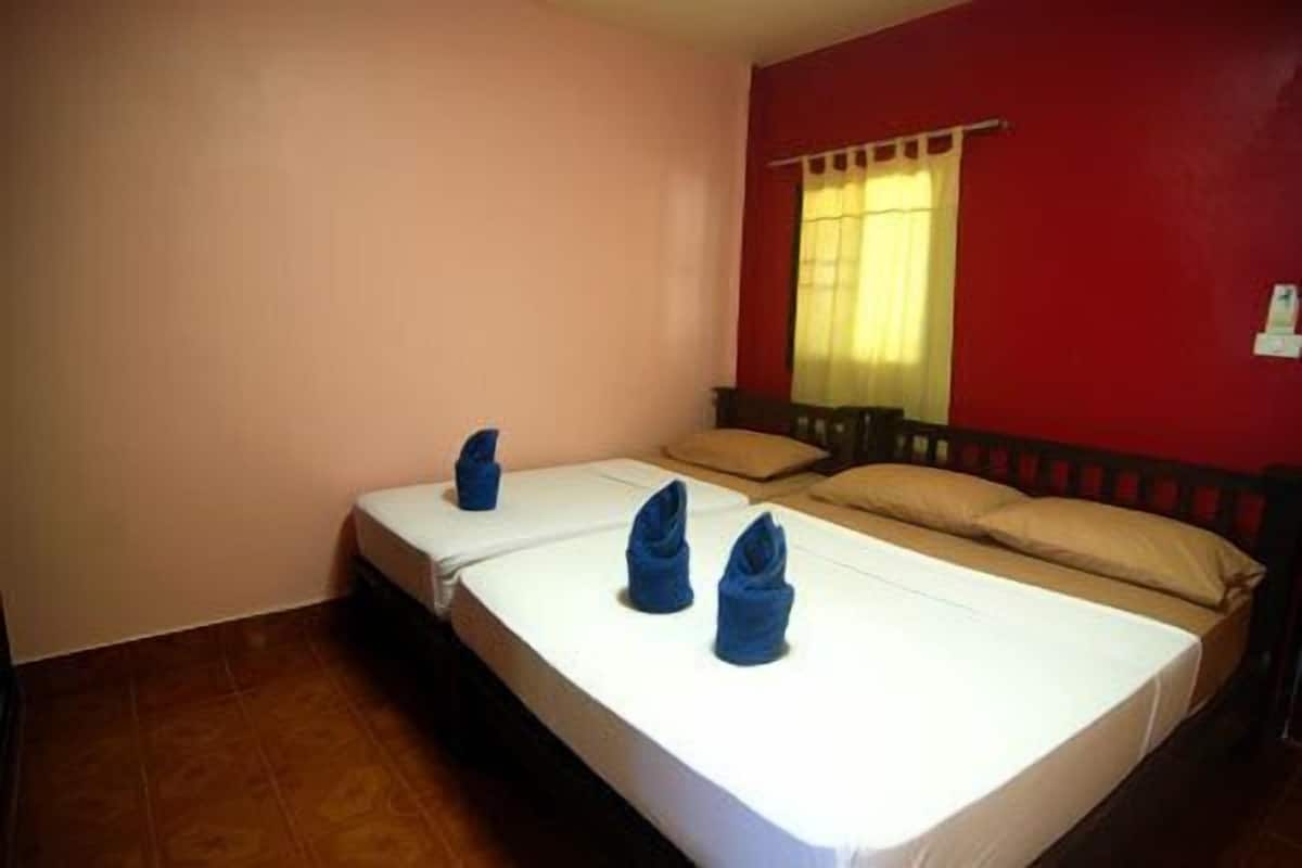 Quarto com duas camas, janela com cortinas amarelas e parede vermelha.