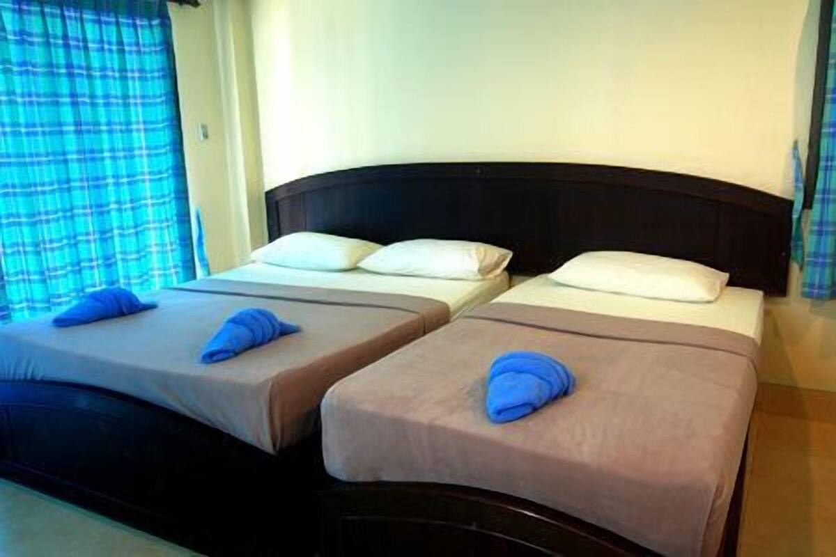 Duas camas de solteiro com cabeceiras, roupa de cama branca e toalhas azuis.