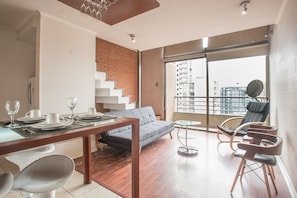 Ein moderner Wohnraum mit Essbereich, einer Couch und einem Balkon mit Blick auf die Stadt.