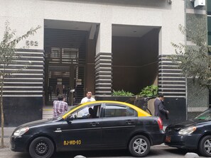 A black car with yellow accents parked in front of a building with a number 562 sign. - Altura Suites (Santiago)