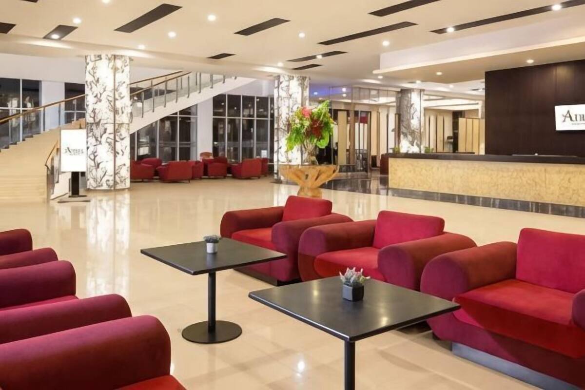 En entréhall med röda sittplatser, en receptionsdisk och en trappa.