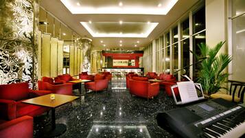 A lobby with red seating, a piano, and a laptop on a table.