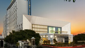 A modern hotel with a prominent entrance, large windows, and a well-maintained garden area.