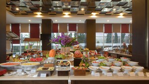 A buffet with various food items and a large floral centerpiece.