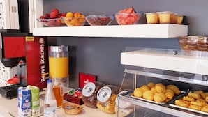En frukostbuffé med ett urval av olika frukter, bakverk och drycker.