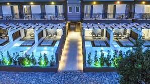 A multi-story hotel with outdoor seating areas and a central pool. - Royal Hotel and Suites (Kassandra)