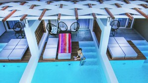 A pool area with lounge chairs, a striped towel, and a person in the water. - Royal Hotel and Suites (Kassandra)