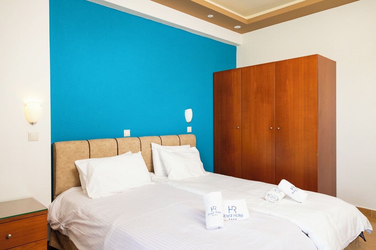 A hotel room with a bed, a wooden wardrobe, and a blue wall.