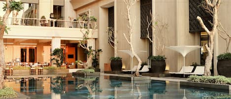 Un patio de hotel con piscina, mobiliario exterior y zona de comedor.