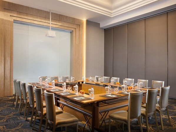 Un salón de conferencias con una mesa larga, sillas y una pantalla para proyector.