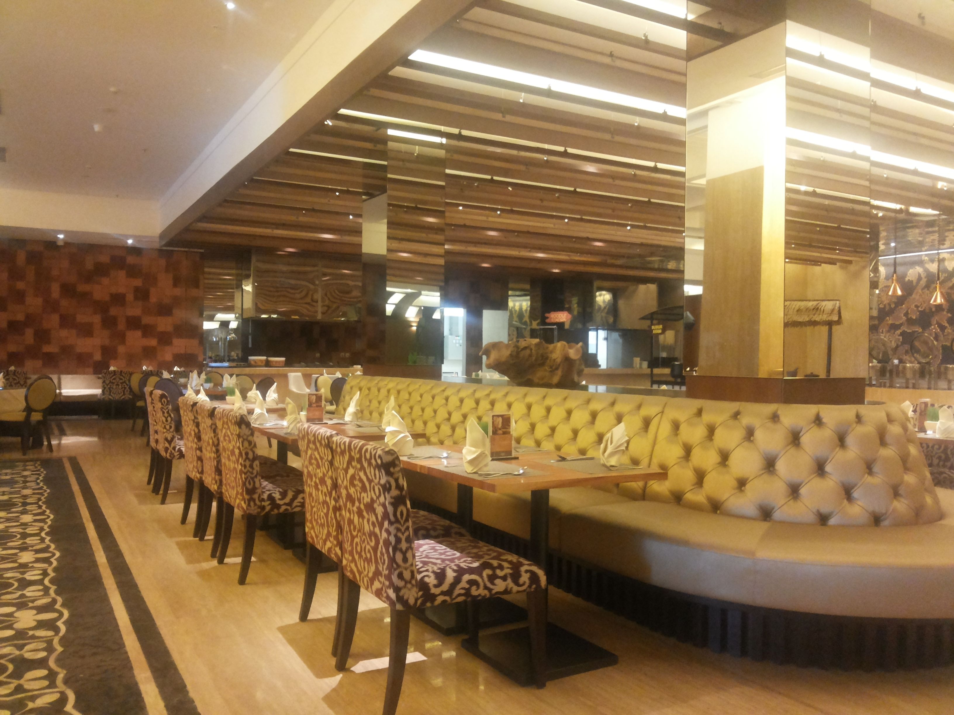 A restaurant with a long table, patterned chairs, and a tufted bench.