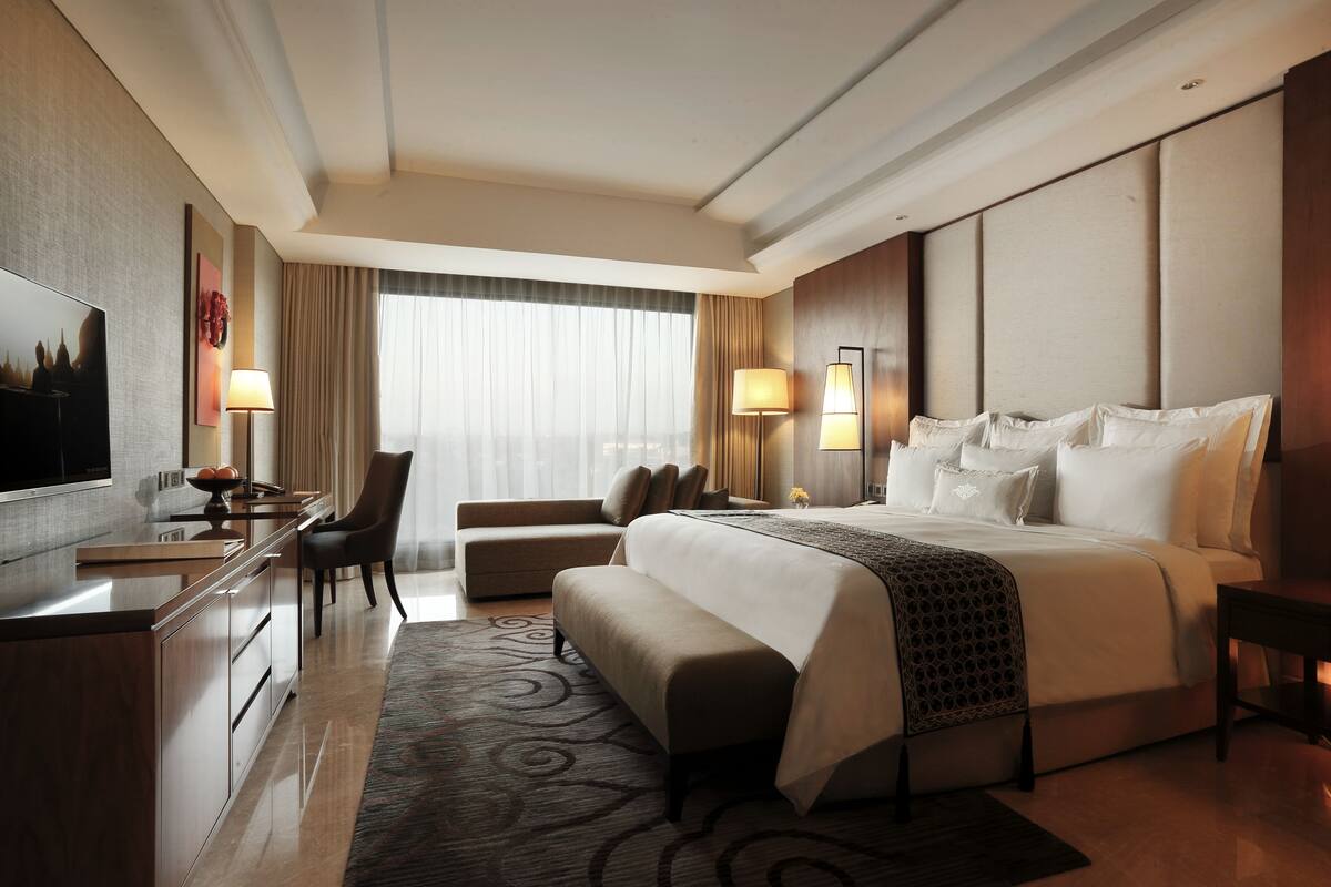 Una habitación de hotel moderna con una cama grande, un escritorio, un sofá y un televisor.