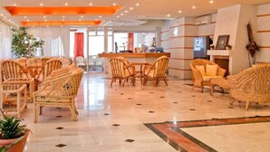 A spacious hotel lobby with wicker furniture, a tiled floor, and a view into the dining area. - Dedalos Beach Hotel (Rethymno)
