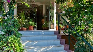 A staircase leading to a building entrance, surrounded by lush greenery and flowering plants. - Dedalos Beach Hotel (Rethymno)