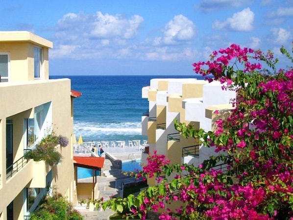 Un hôtel situé sur la côte, doté d’une piscine, de balcons et offrant une vue sur la mer.