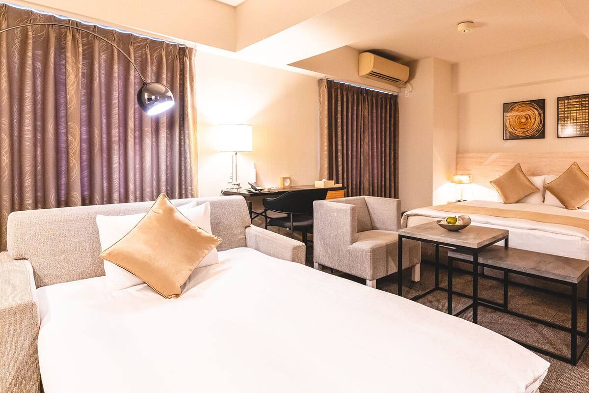 Een hotelkamer met twee bedden, een bureau, een stoel, een bijzettafeltje en een lamp.