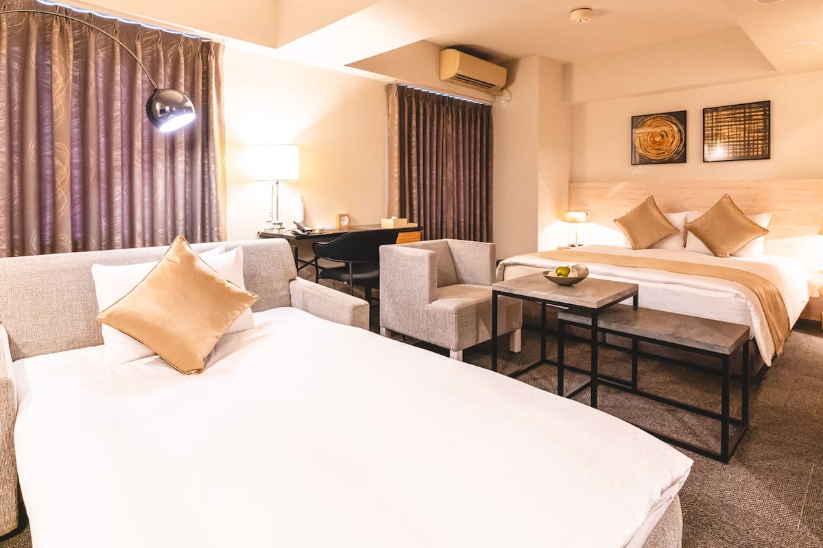 Een hotelkamer met twee bedden, een bureau, een stoel en een klein tafeltje.