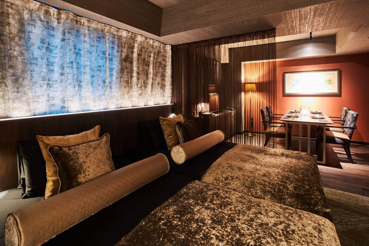 Een moderne hotelkamer met een groot bed, een zithoek en een groot raam met gordijnen.