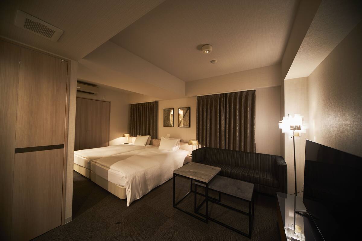 Een hotelkamer met een tweepersoonsbed, een slaapbank, een televisie en een bureau.